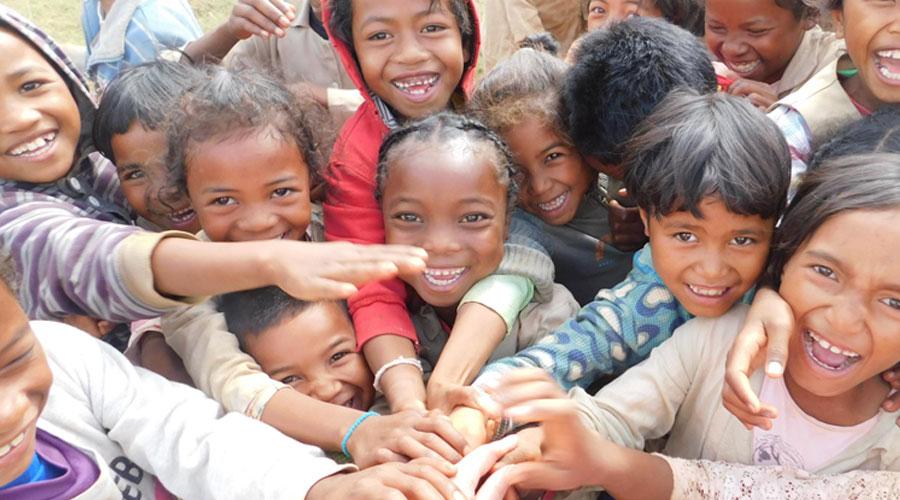 group of children in madagascar putting their hands together while smiling at the camera