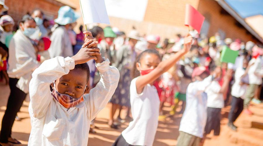 children at school in madagascar waving flags in the air